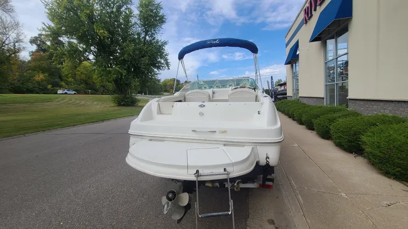 Slide: The Image of 2002 Sea Ray 225 Weekender boat with blue canopy, parked near a building. - 5