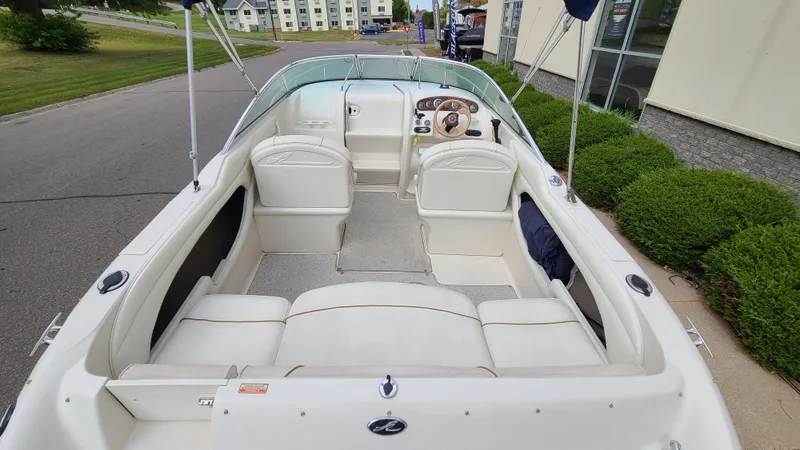 Slide: The Image of 2002 Sea Ray 225 Weekender boat interior with white seating and dashboard. - 6