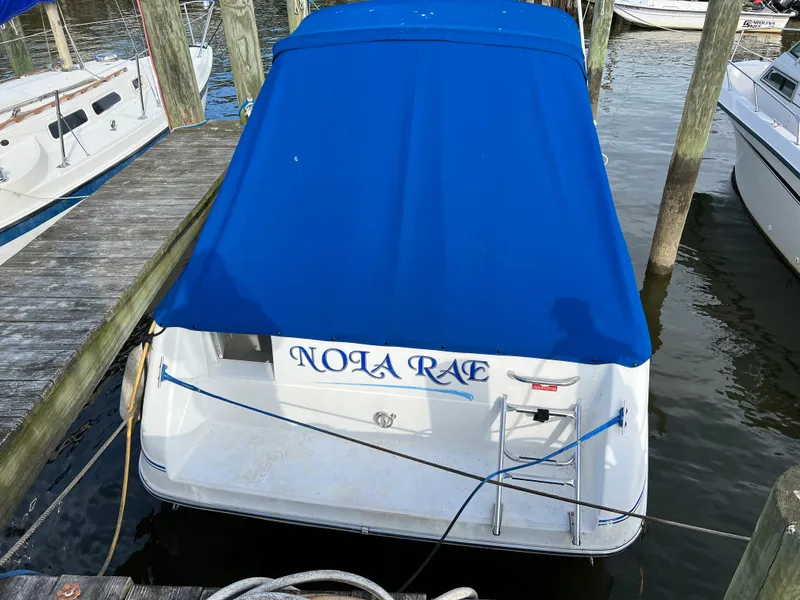 Slide: The Image of 1991 Sea Ray Sundancer 220 docked, blue cover, named "NOLA RAE". - 1