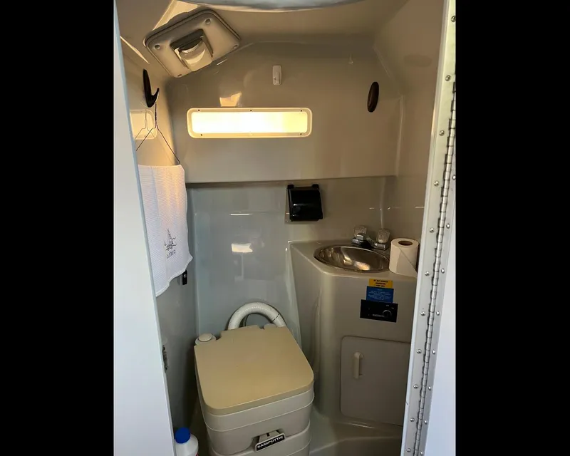 Slide: The Image of Compact bathroom in 1991 Sea Ray Sundancer 220 boat with toilet, sink, and window. - 10