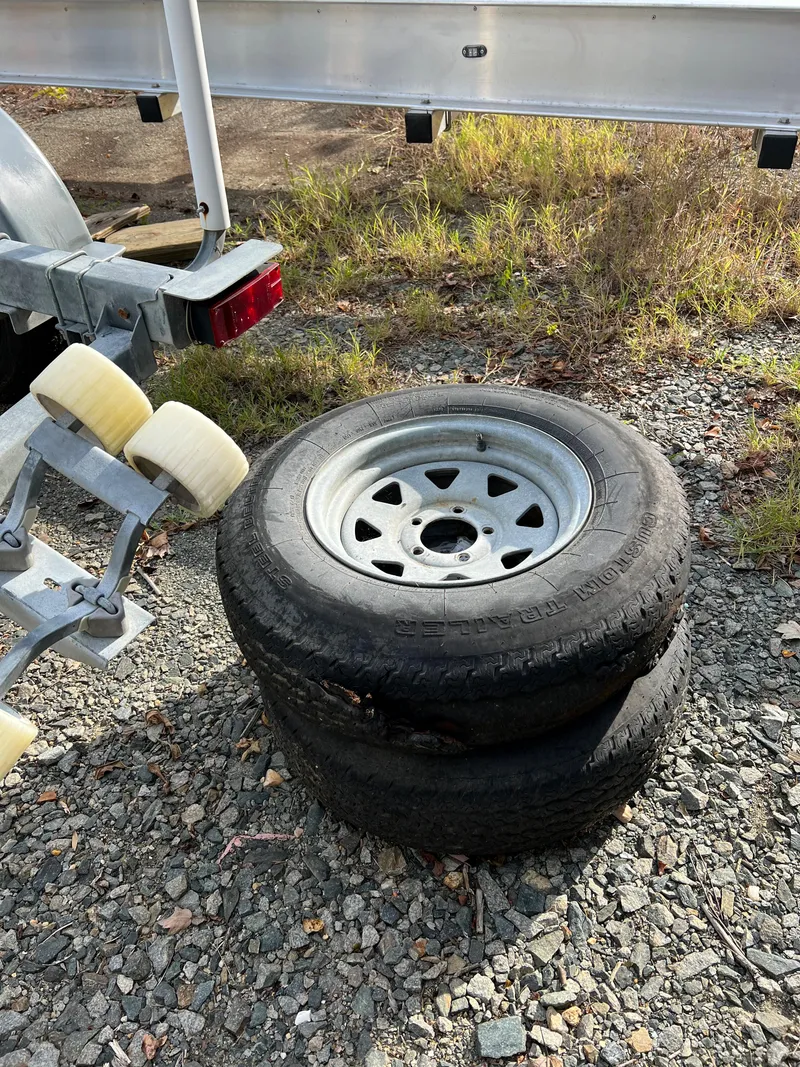 Slide: The Image of Stacked trailer tires beside a Sea Ray 1991 Sundancer 220 boat trailer. - 15