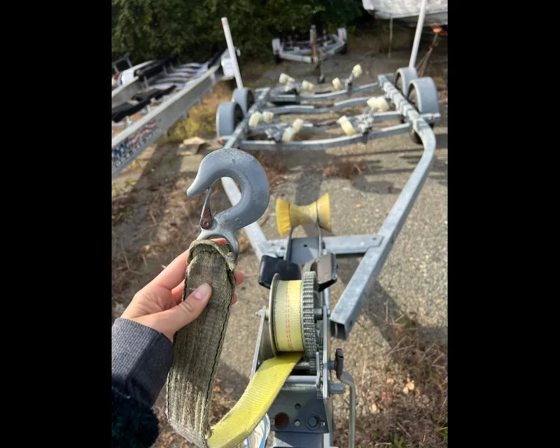 Slide: The Image of Hand holding a boat trailer hook, Sea Ray 1991 Sundancer 220 trailer in background. - 17