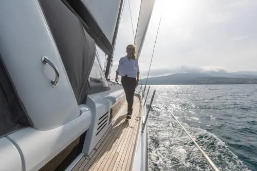 Slide: The Image of Woman walking on deck of 2026 Beneteau Oceanis Yacht 60, sailing on open water. - 8