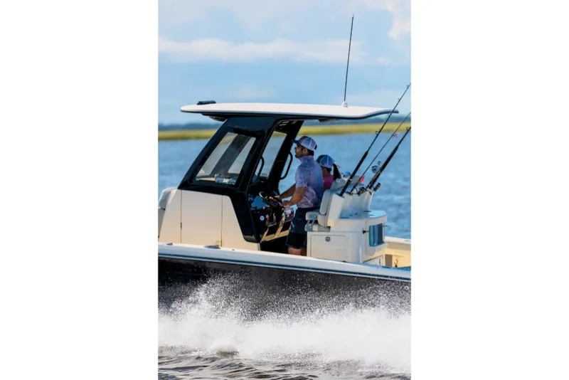 Slide: The Image of 2023 Scout 281 XSS boat cruising on water with fishing rods. - 13