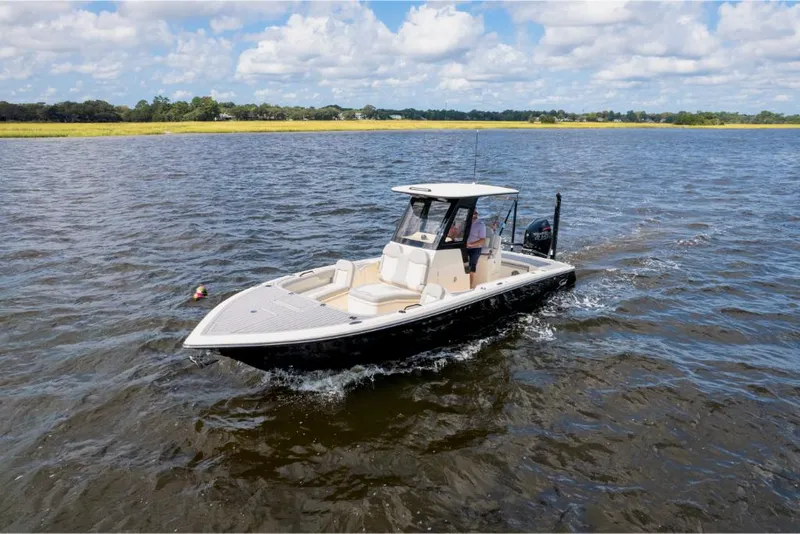 Slide: The Image of 2023 Scout 281 XSS boat cruising on a lake under a partly cloudy sky. - 25
