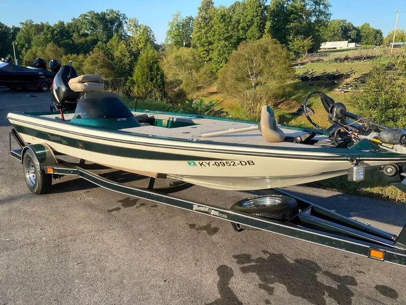 Slide: The Image of 2002 Bumble Bee 18 boat on trailer, parked outdoors, surrounded by trees. - 3