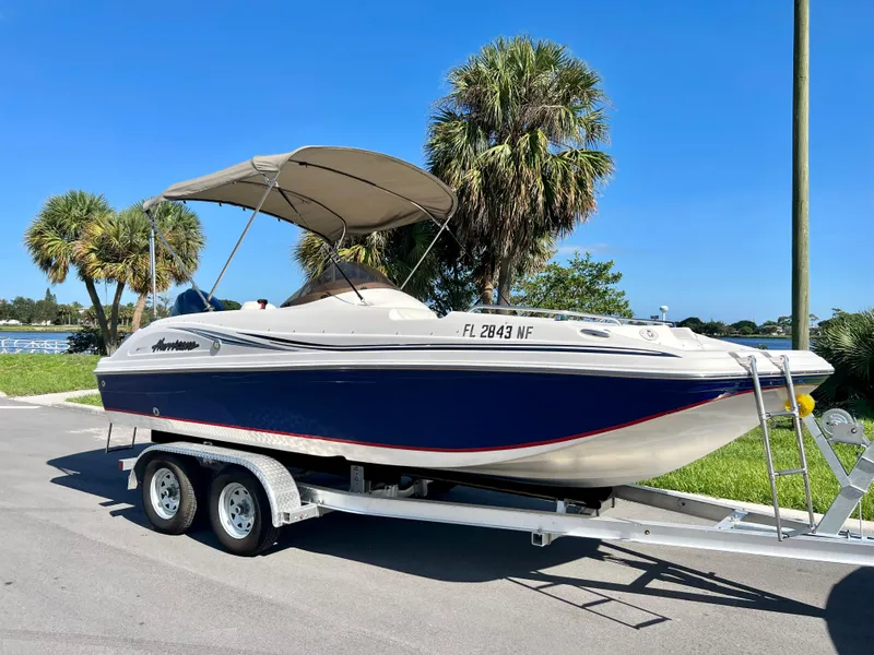 Slide: The Image of 2006 Hurricane 194 boat on trailer, parked near palm trees under clear blue sky. - 13