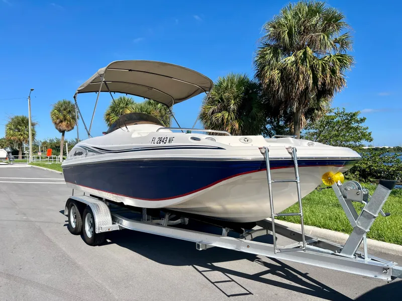 Slide: The Image of 2006 Hurricane 194 boat on trailer, parked near palm trees under clear blue sky. - 15