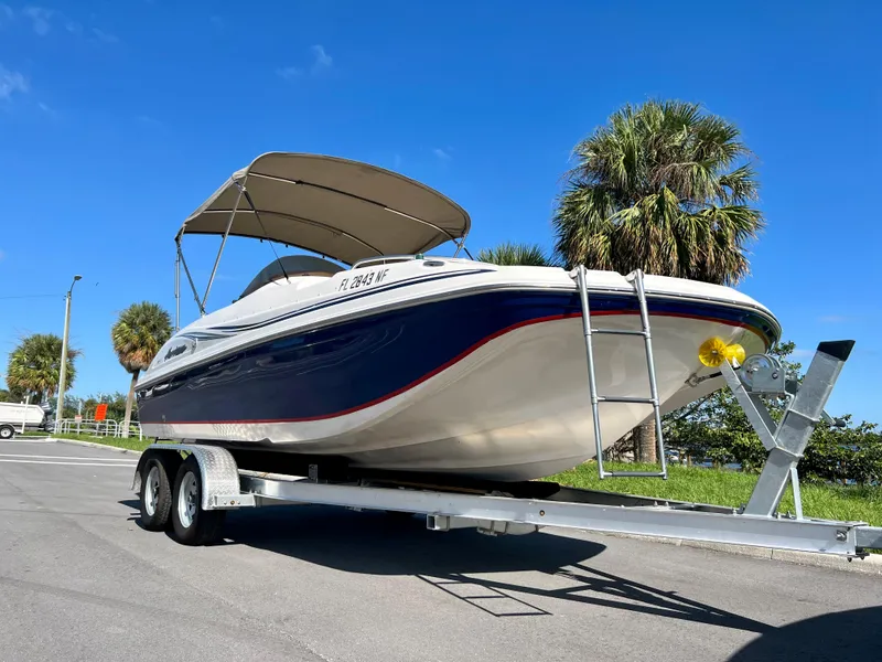 Slide: The Image of 2006 Hurricane 194 boat on trailer, blue and white, parked near palm trees. - 16