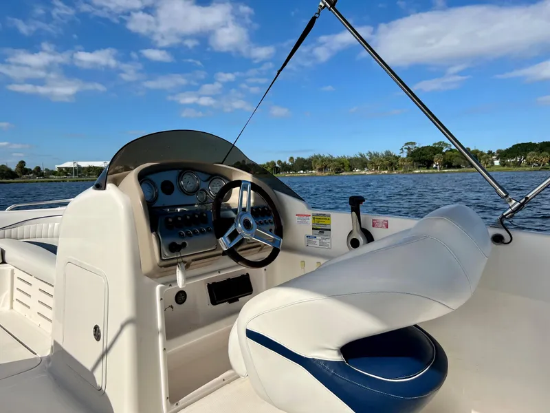 Slide: The Image of 2006 Hurricane 194 boat interior with steering wheel, dashboard, and seating on a sunny day. - 30