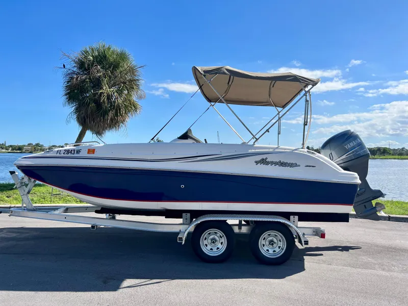 Slide: The Image of 2006 Hurricane 194 boat on trailer by a lake under clear blue sky. - 5