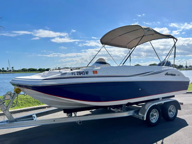 Slide: The Image of 2006 Hurricane 194 boat on trailer by a lake under a clear blue sky. - 6