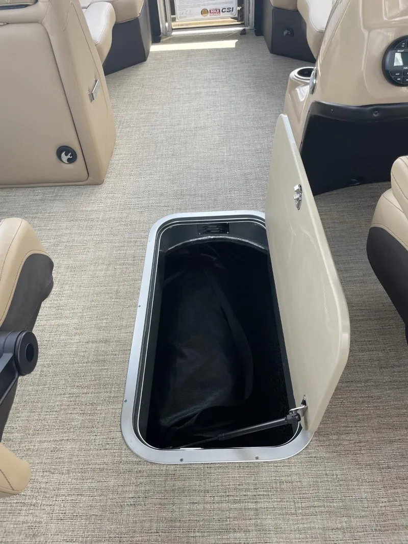 Slide: The Image of 2022 Barletta Cabrio 22QC interior with open storage compartment, beige seating, and carpeted floor. - 11