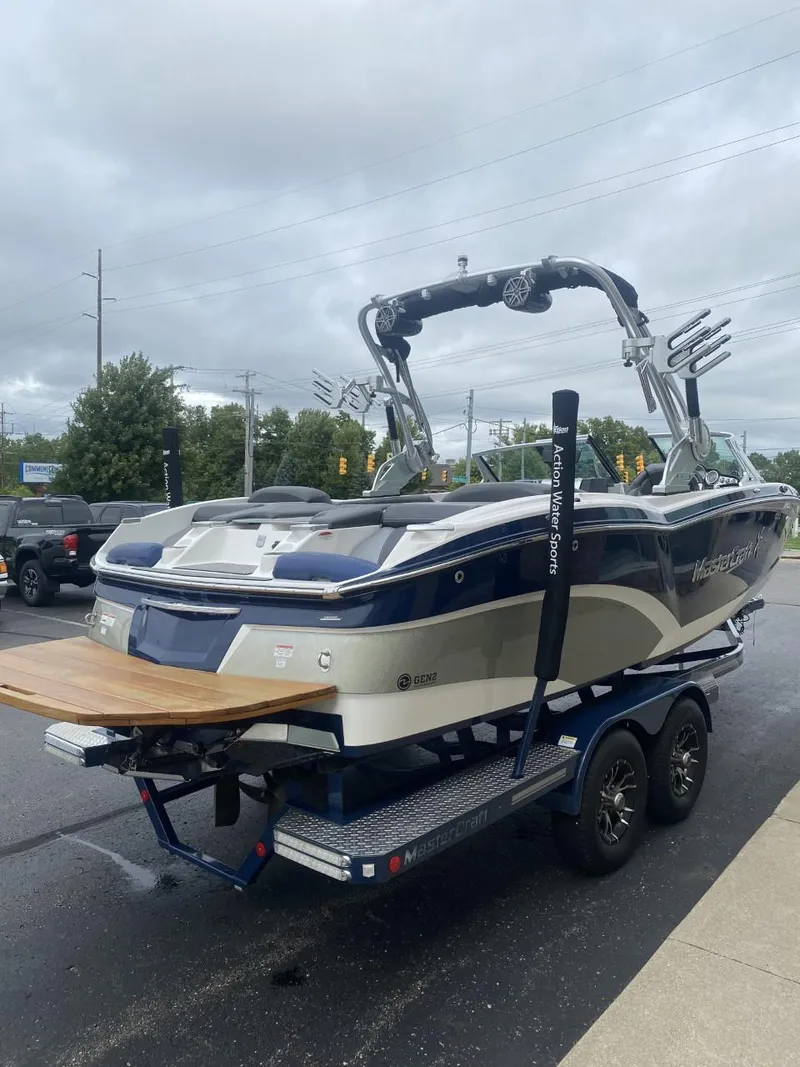 Slide: The Image of 2016 MasterCraft X23 boat on trailer, parked outdoors, with overcast sky. - 3