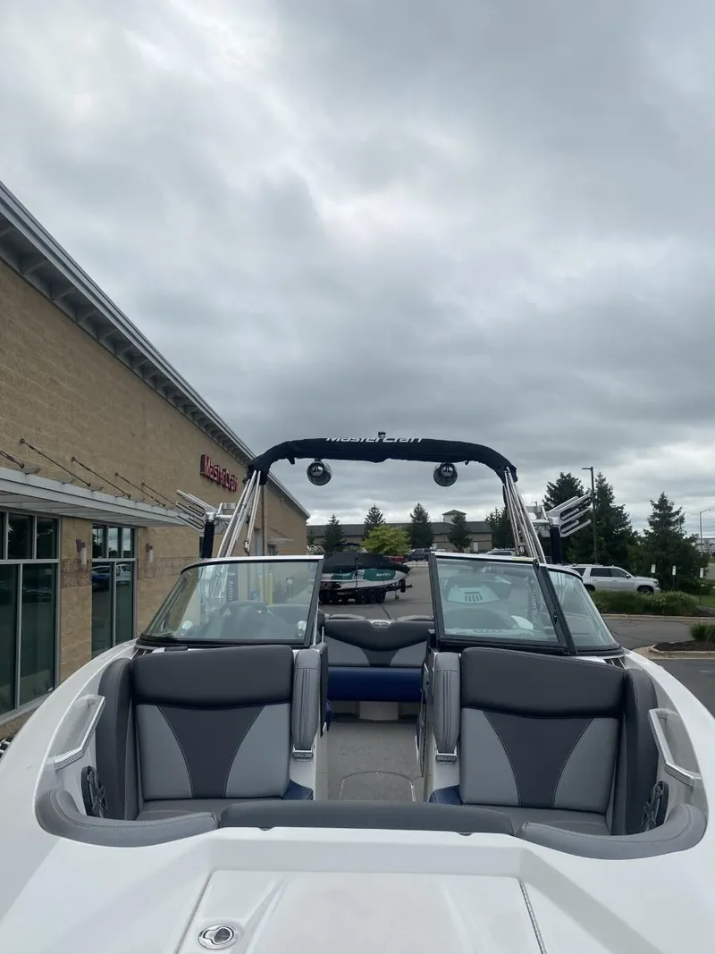Slide: The Image of 2016 MasterCraft X23 boat with sleek seating, parked outdoors under cloudy skies. - 4