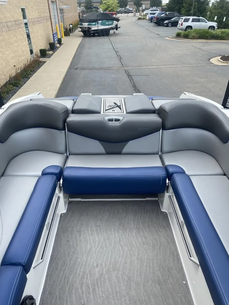 Slide: The Image of 2016 MasterCraft X23 boat interior with blue and gray seating, parked outdoors. - 8