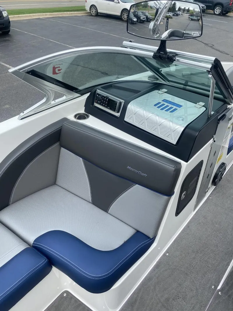 Slide: The Image of 2016 MasterCraft X23 boat interior with gray and blue seating, dashboard, and mirror. - 9