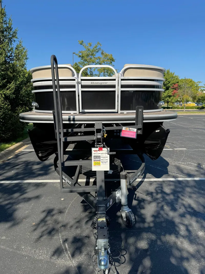 Slide: The Image of 2023 Ranger Reata 243C pontoon boat on trailer in parking lot. - 2