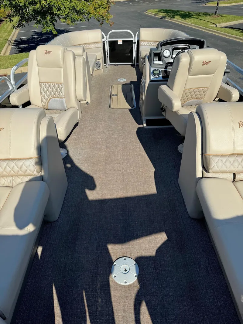 Slide: The Image of 2023 Ranger Reata 243C pontoon boat interior with beige seating and steering console. - 3