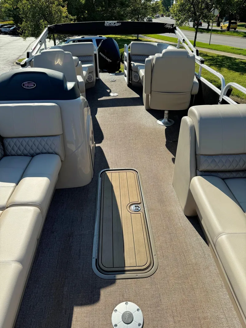 Slide: The Image of 2023 Ranger Reata 243C pontoon boat interior with beige seating and wood accents. - 4