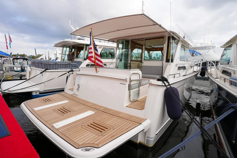 Slide: The Image of 2025 Sabre 45 Salon Express yacht docked, featuring a spacious deck and American flag. - 13