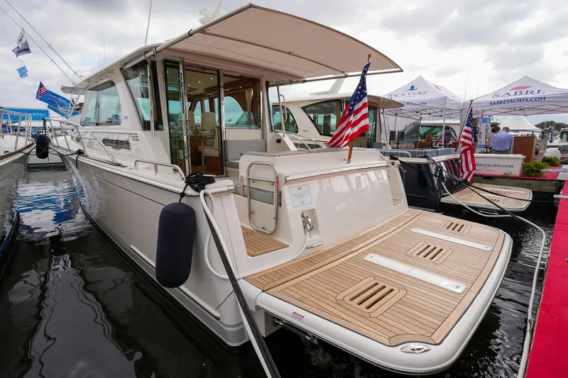 Slide: The Image of 2025 Sabre 45 Salon Express yacht docked at marina, featuring elegant design and American flags. - 14