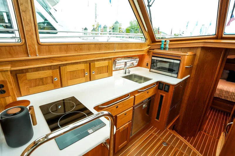Slide: The Image of 2025 Sabre 45 Salon Express yacht kitchen with modern appliances and wooden cabinetry. - 26