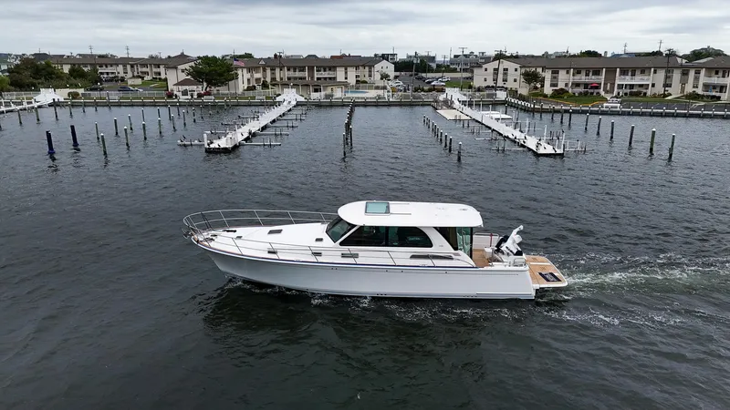 Slide: The Image of 2025 Sabre 45 Salon Express yacht cruising in a marina with docked boats. - 6
