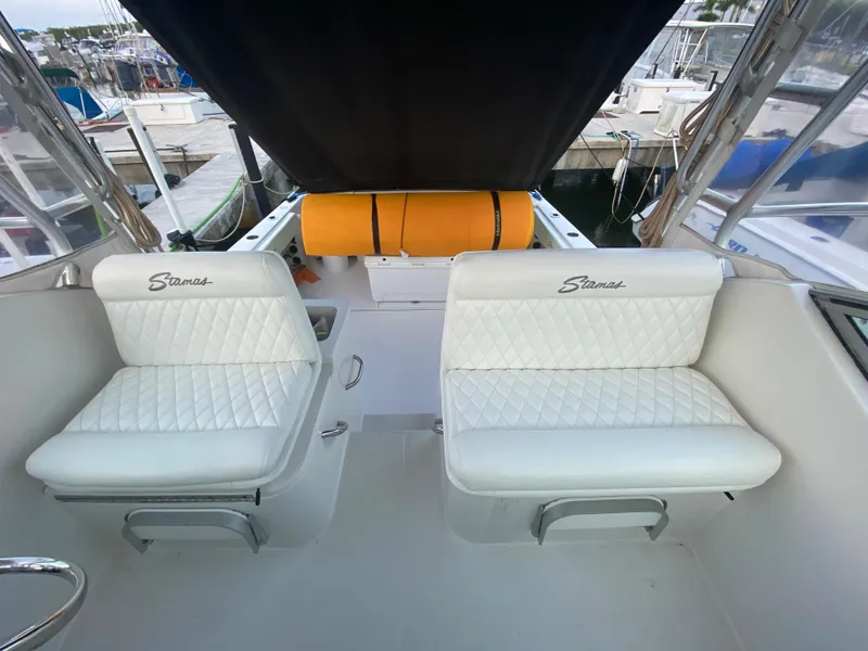 Slide: The Image of 2006 Stamas 320 Express boat interior with white seating and marina background. - 28