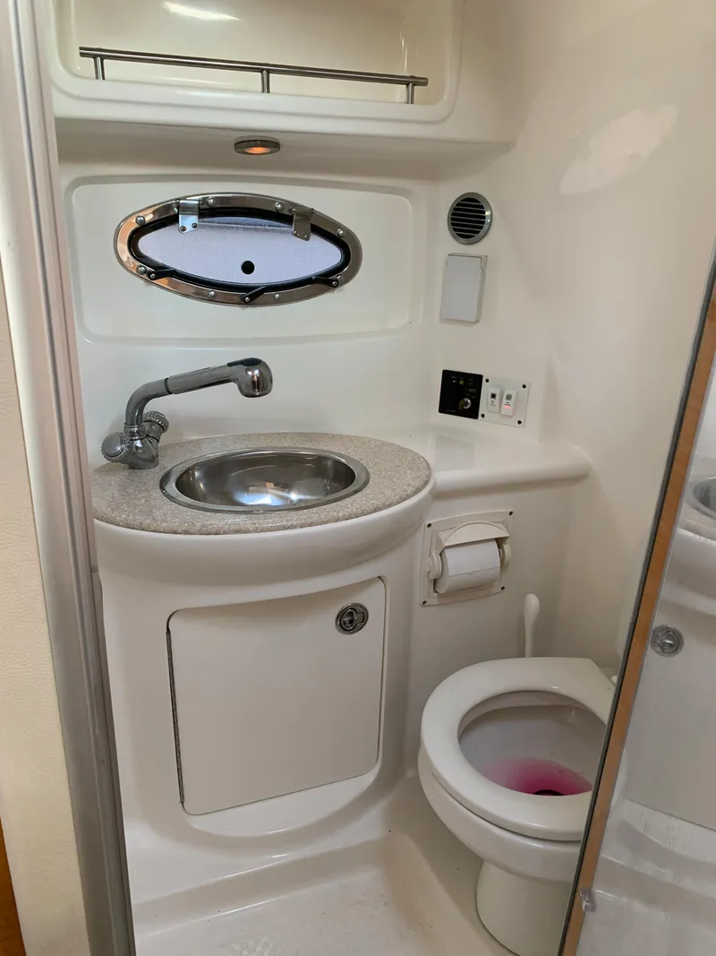 Slide: The Image of 2006 Chaparral 276 Signature boat bathroom with sink, toilet, and porthole window. - 16