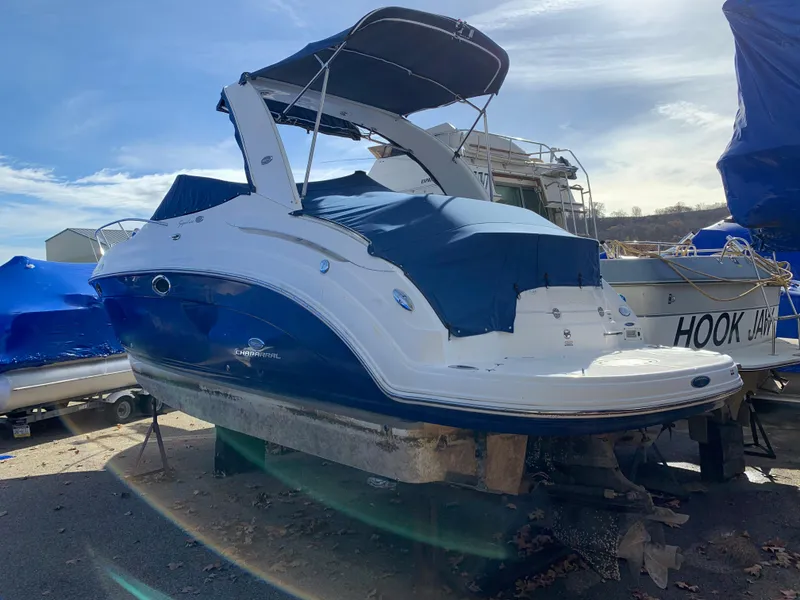 Slide: The Image of 2006 Chaparral 276 Signature boat with blue and white exterior, docked on land. - 2
