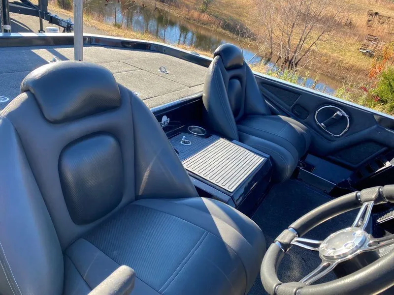 Slide: The Image of 2014 Ranger Z520C boat interior with leather seats and steering wheel, near a pond. - 14