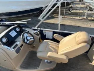 Slide: The Image of 2019 Godfrey 259CBD boat cockpit with beige captain's chair and steering wheel. - 9