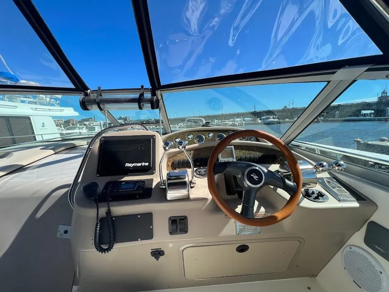 Slide: The Image of 2000 Sea Ray 34 DA yacht helm with Raymarine electronics, wooden steering wheel, and marina view. - 10