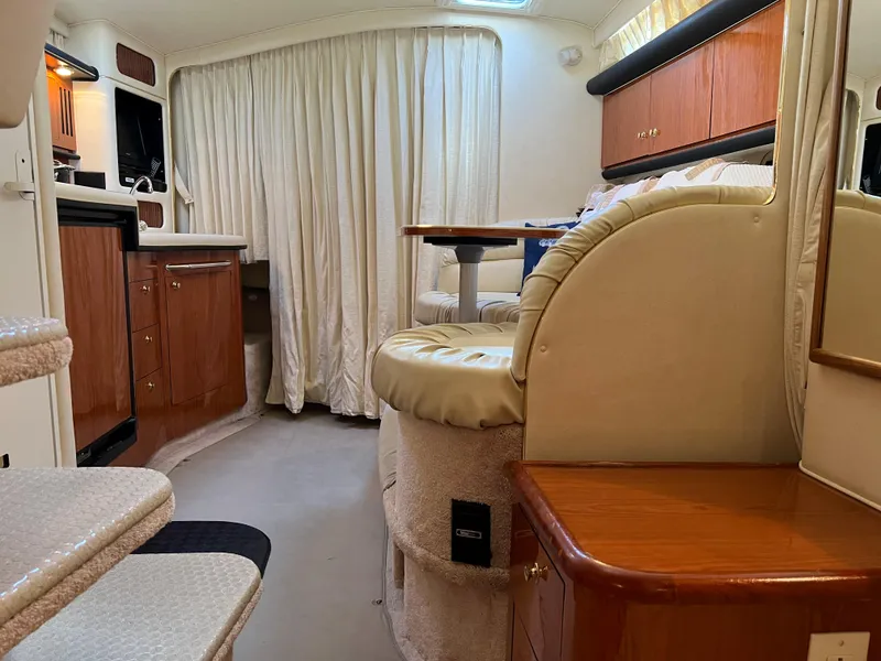 Slide: The Image of Interior of 2000 Sea Ray 34 DA yacht with cozy seating and wooden cabinetry. - 28