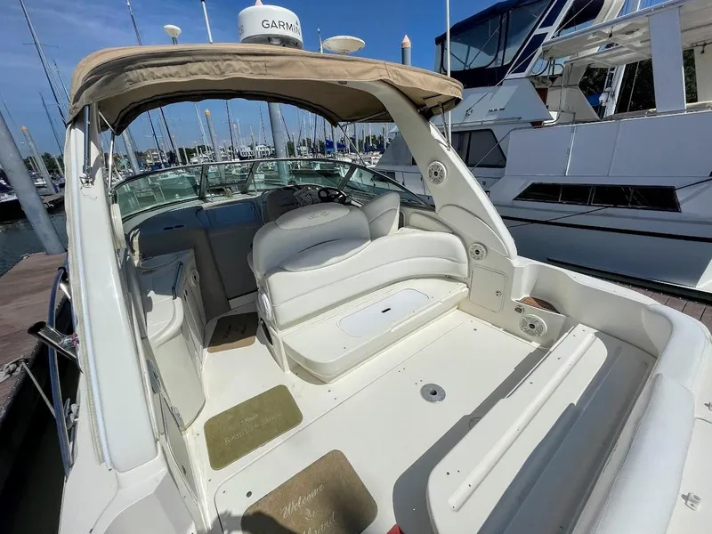 Slide: The Image of 2002 Sea Ray 340 Sundancer boat interior at marina, featuring seating and canopy. - 16