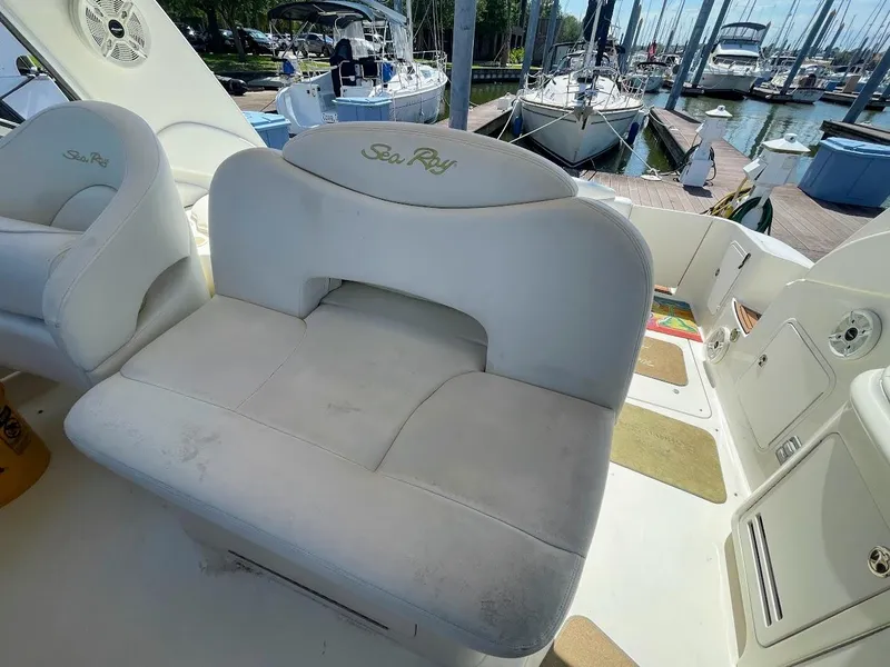 Slide: The Image of 2002 Sea Ray 340 Sundancer boat seating area with marina background. - 17