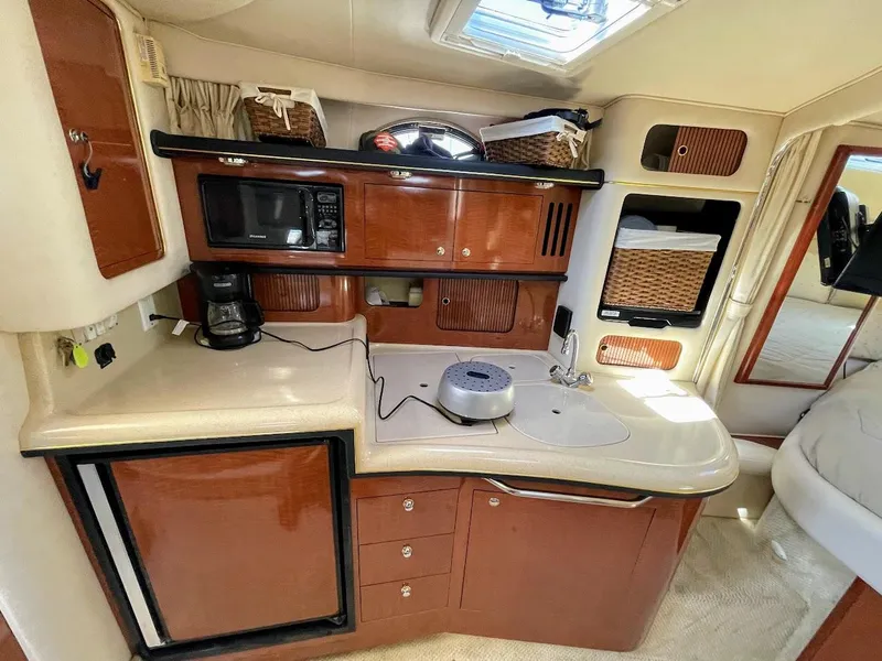 Slide: The Image of 2002 Sea Ray 340 Sundancer galley with microwave, fridge, and storage baskets. - 28