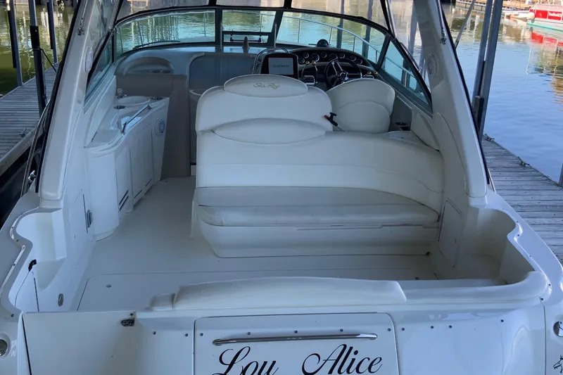 Slide: The Image of 2000 Sea Ray Sundancer boat interior with white seating and helm, docked by the water. - 3