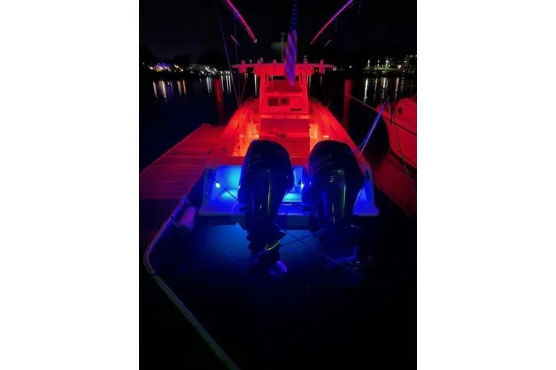 Slide: The Image of 2005 Marlago 35 boat illuminated with vibrant red and blue lights at night. - 21