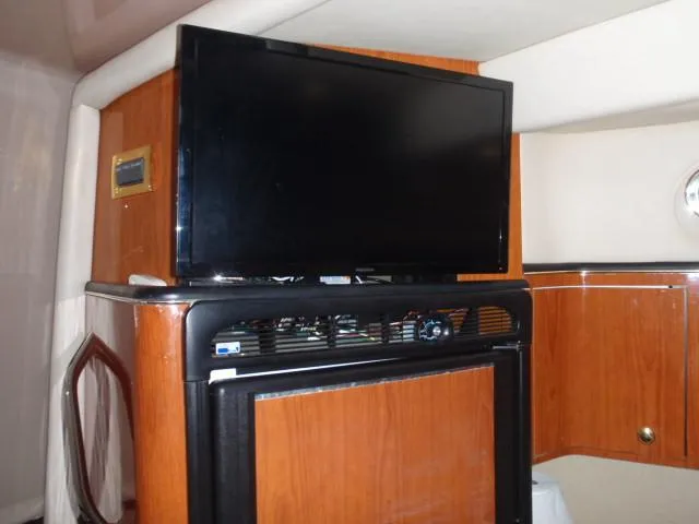 Slide: The Image of 1999 Sea Ray 410 Express Cruiser interior with TV and wooden cabinetry. - 23