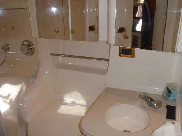 Slide: The Image of Bathroom interior of 1999 Sea Ray 410 Express Cruiser with sink and storage cabinets. - 28