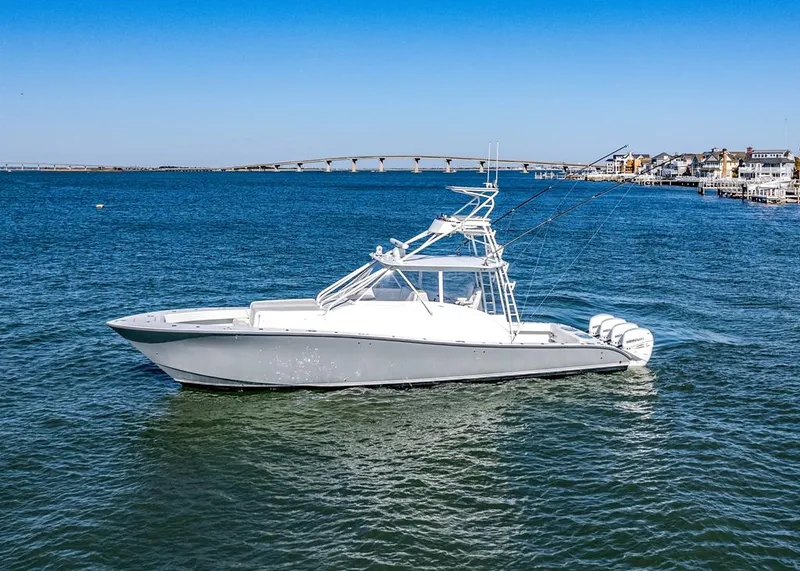 The Image of 2021 Conch 47 boat on calm water with a bridge and buildings in the background. - 0