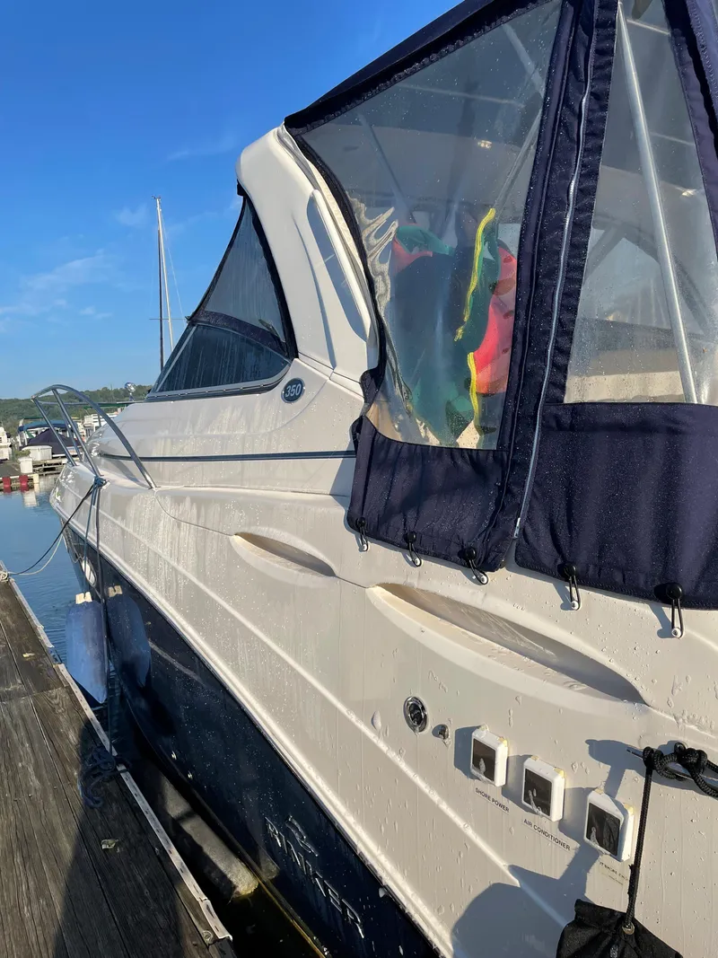 Slide: The Image of 2007 Rinker 350 Express Cruiser docked, featuring sleek design and blue canopy. - 7