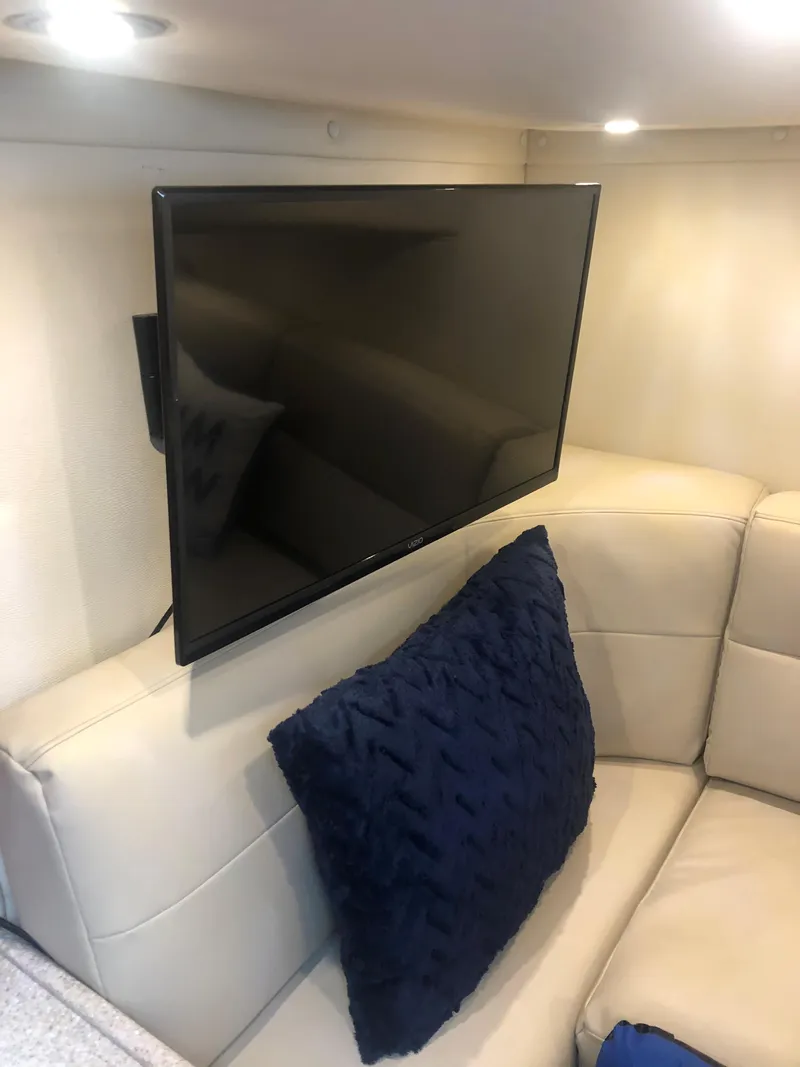 Slide: The Image of 2007 Rinker 350 Express Cruiser interior with TV and blue pillow on beige sofa. - 9