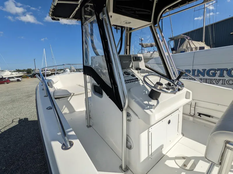 Slide: The Image of 2007 Sea Boss 235 Center Console boat with steering wheel and controls, docked outdoors. - 17