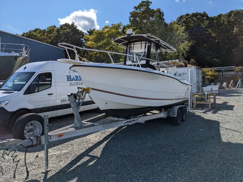 Slide: The Image of 2007 Sea Boss 235 Center Console boat on trailer, parked outdoors near a van. - 2