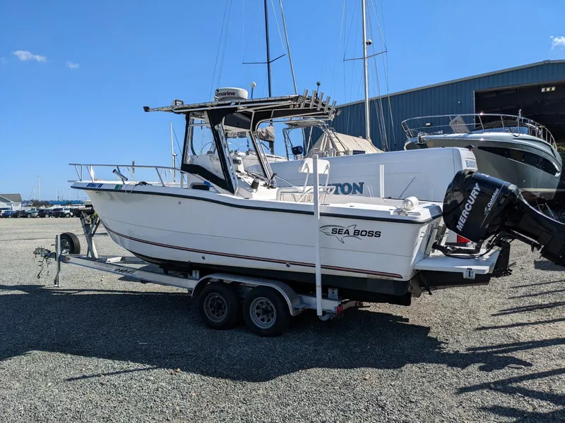 Slide: The Image of 2007 Sea Boss 235 Center Console boat on trailer, parked outdoors near other boats. - 3