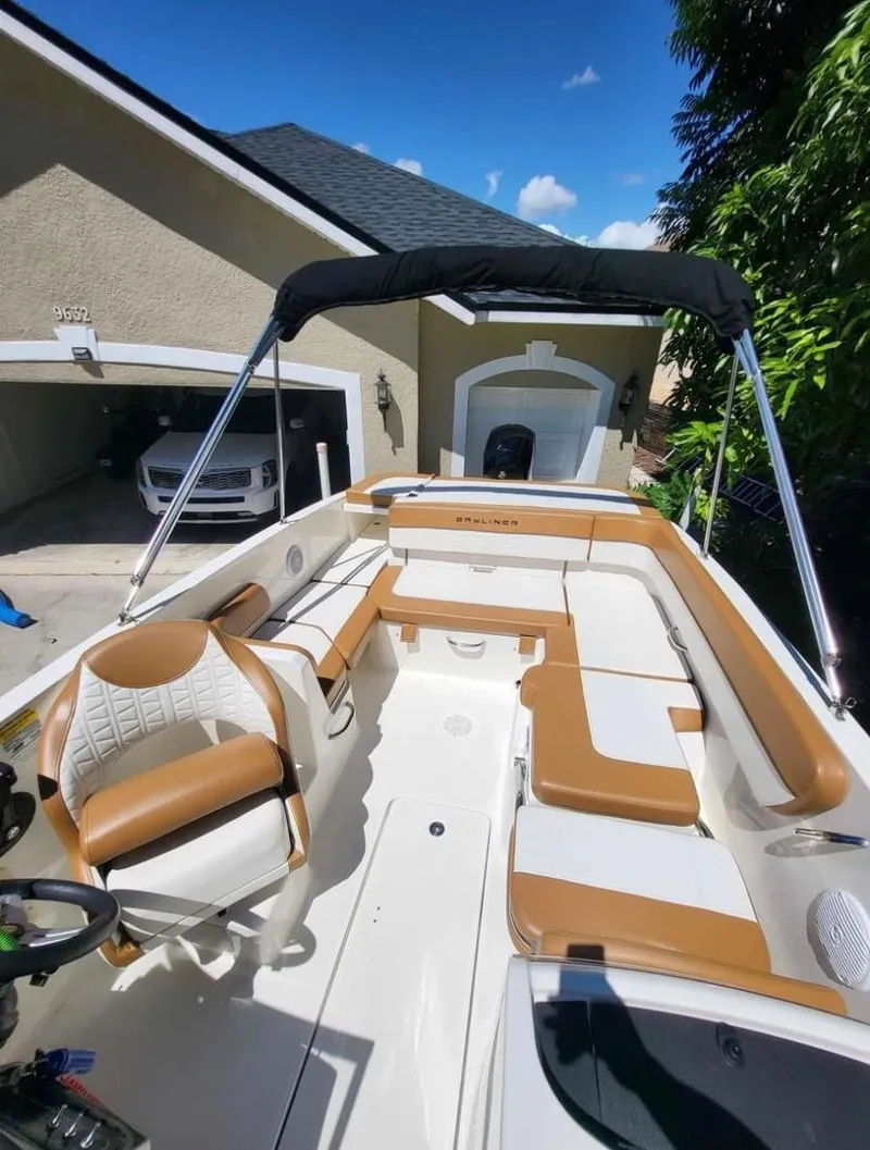 Slide: The Image of 2021 Bayliner VR6 Bowrider OB with tan and white interior, parked in a driveway. - 11