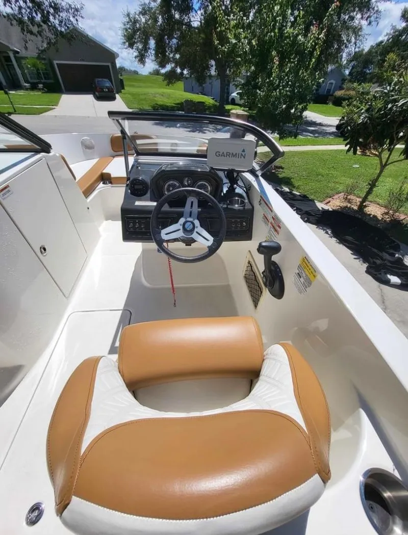 Slide: The Image of 2021 Bayliner VR6 Bowrider OB cockpit with tan and white seating, steering wheel, and Garmin navigation. - 9